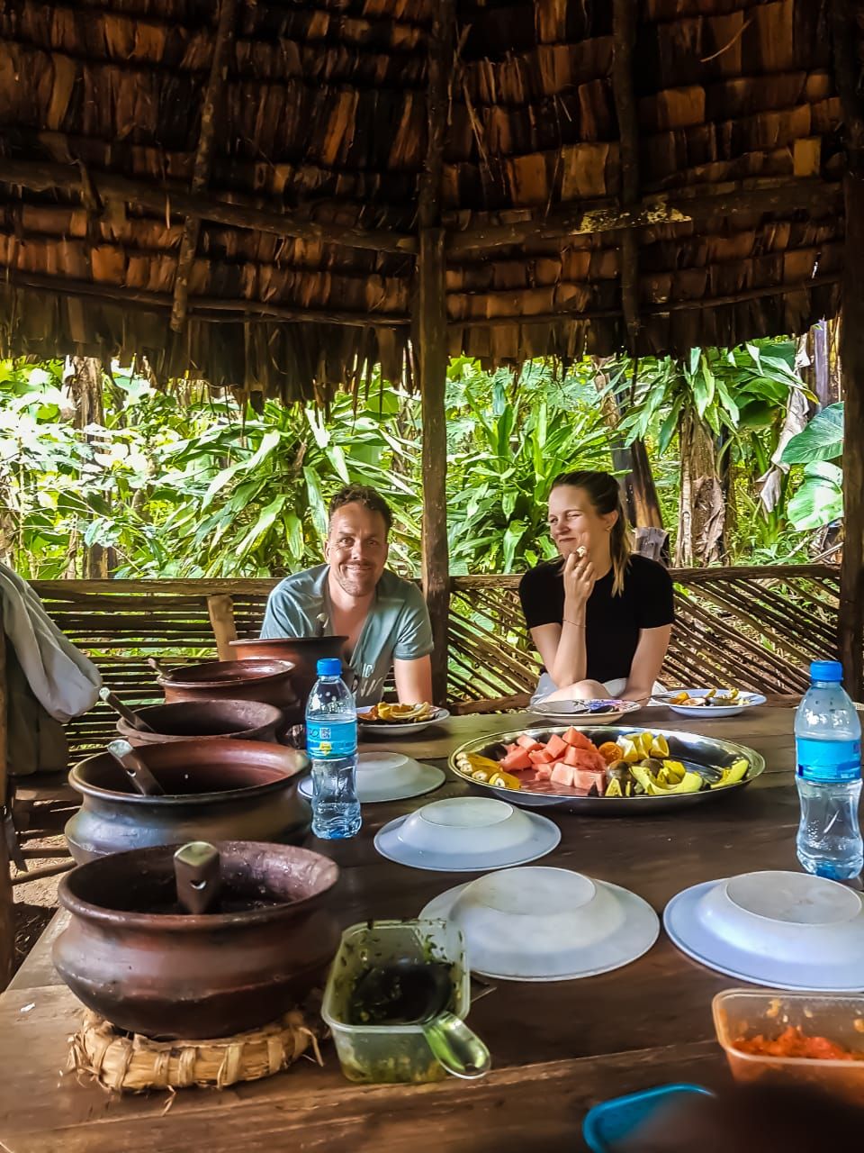 A shared meal from clay pots under the thatched shelter