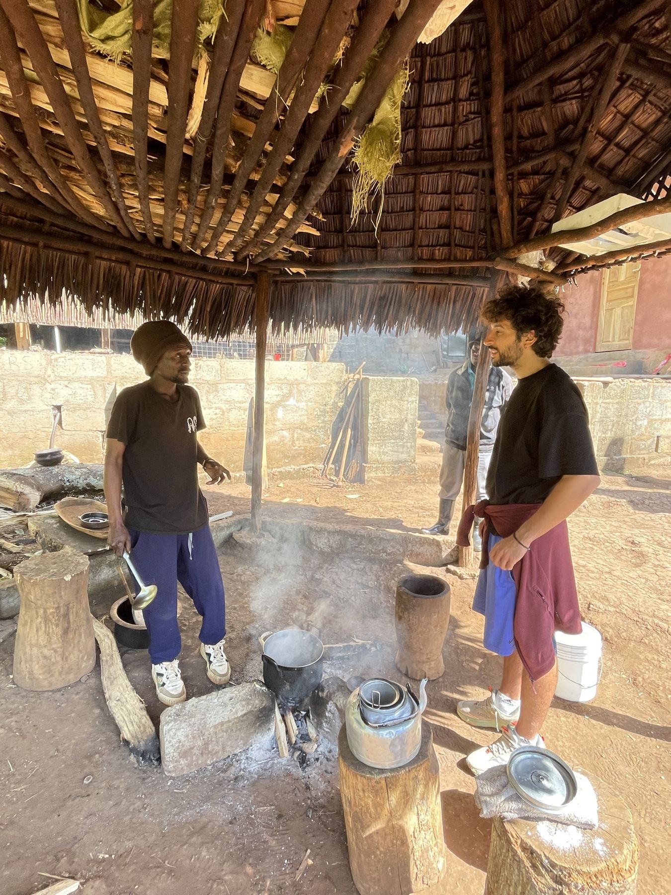 The kettle on the fire under the thatched shelter